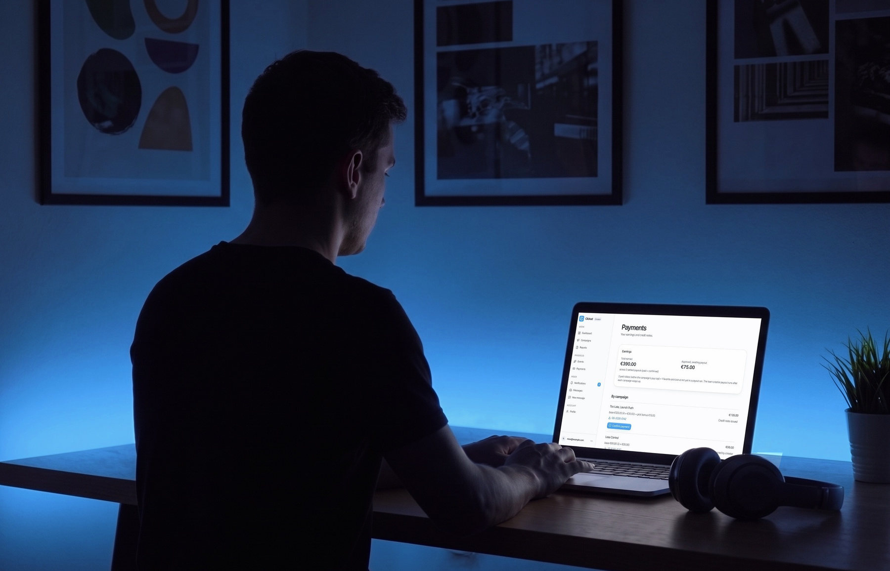 A creator works in Clicked on a laptop at the desk in their room. The Payments page is open, with the total earned and the earnings for each campaign.